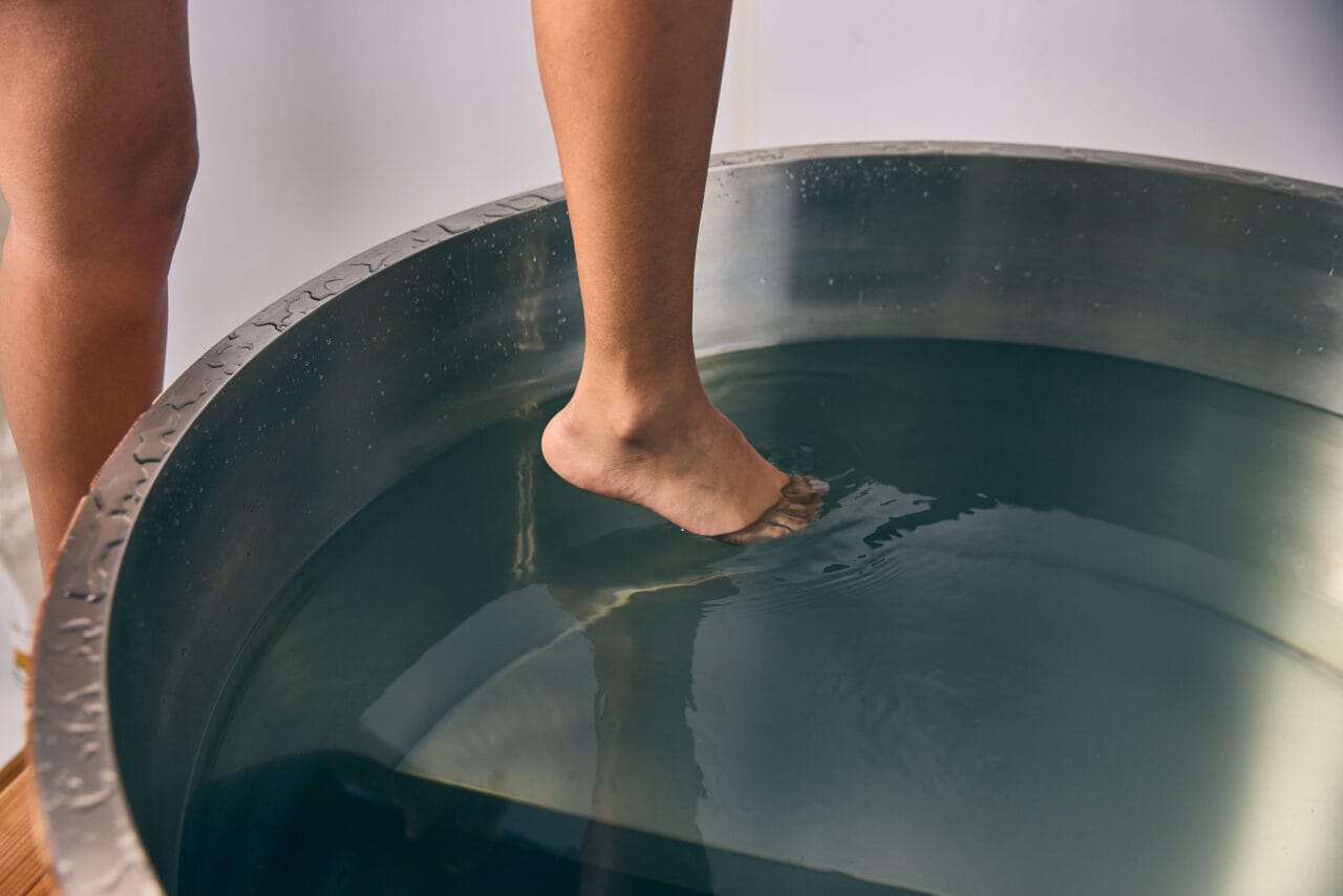 A person dipping a toe in a tub of water