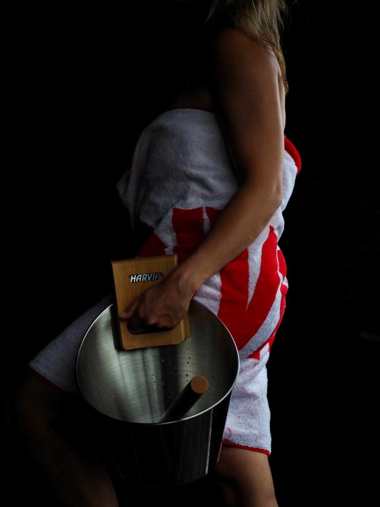 The picture shows a woman carrying a sauna bucket.